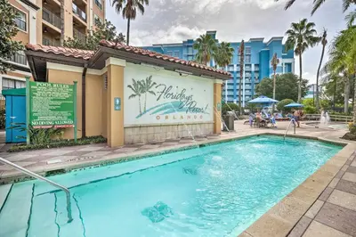 a swimming pool at a resort with a building and palm trees at Disney Good Neighbor Resort Condo Less Than 4 Mi to WDW! in Orlando