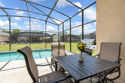 a patio with a table and chairs and a pool at Disney Area 4BR Home with Heated Private Pool in Kissimmee