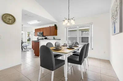 a dining room and kitchen with a table and chairs at Disney Area 4BR Home with Heated Private Pool in Kissimmee