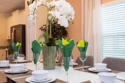 a dining room table with vases with flowers in them at Magnificent 5Bd w/ Pool Close to Disney @Storey Lake 4800 in Kissimmee