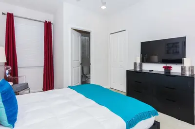 a bedroom with a bed and a tv and red curtains at Magical Retreat: Luxurious Home near Disney World in Kissimmee