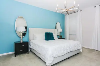 a blue bedroom with a white bed and a mirror at Magical Retreat: Luxurious Home near Disney World in Kissimmee