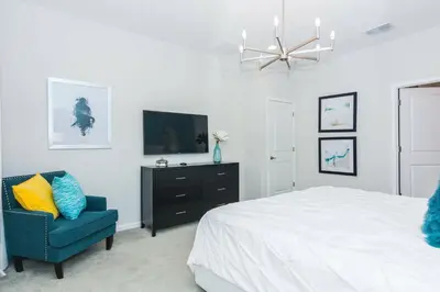 a bedroom with a bed and a tv and a chair at Magical Retreat: Luxurious Home near Disney World in Kissimmee