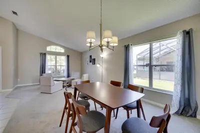 a dining room and living room with a table and chairs at Kissimmee Getaway with Pool about 7 Mi to Disney! in Kissimmee