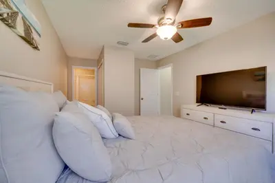 a bedroom with a large bed and a flat screen tv at Kissimmee Getaway with Pool about 7 Mi to Disney! in Kissimmee