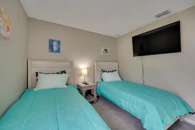a bedroom with two beds and a flat screen tv at Kissimmee Getaway with Pool about 7 Mi to Disney! in Kissimmee