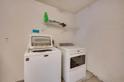 a small kitchen with a tv and a washing machine at Kissimmee Getaway with Pool about 7 Mi to Disney! in Kissimmee