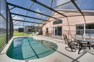 a glass house with a pool and a table and chairs at Kissimmee Getaway with Pool about 7 Mi to Disney! in Kissimmee