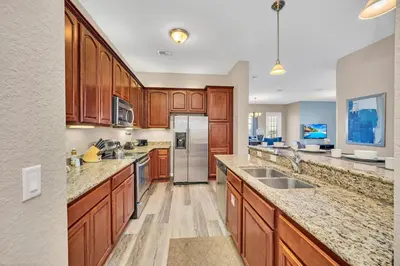 a kitchen with wooden cabinets and stainless steel appliances at Lakeview Condo Directly Next To Pool Near WDW in Orlando