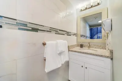 a white bathroom with a sink and a mirror at Fabulous Resort Condo with Heated Pool! in Orlando