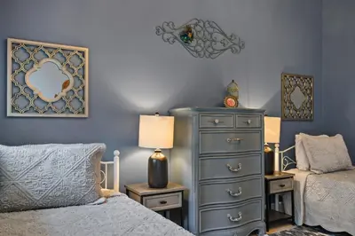 a bedroom with a bed and a dresser with a lamp at Best Location Pet Friendly Fenced Yard in Orlando