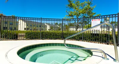 a hot tub with a handrail in front of a fence at Club Cortile 3 Bedroom Condo Resort Pool 8 Miles to Disney in Kissimmee