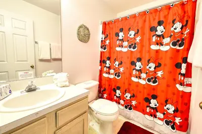 a bathroom with a toilet and a shower curtain with mickeys at Clear Creek 3 Bedroom Home Private Pool 15 Min to Disney in Orlando