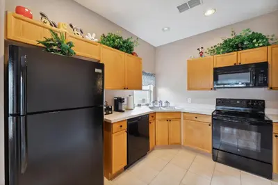 a kitchen with a black refrigerator and wooden cabinets at Vacation Resort Home Right Outside of Disney World Parks with Private Pool home in Kissimmee