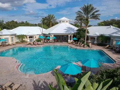 a swimming pool with blue umbrellas and a resort at Vacation Resort Home Right Outside of Disney World Parks with Private Pool home in Kissimmee