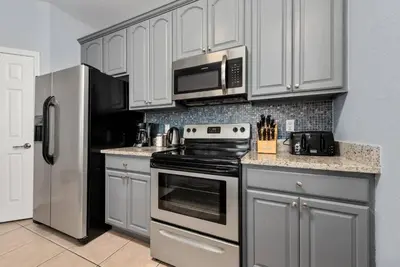 a kitchen with white cabinets and a stove and a refrigerator at Vista Cay Resort in Orlando