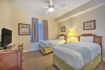 a hotel room with two beds and a flat screen tv at 1 Mi to Disney Condo with Water-View Balcony! in Orlando