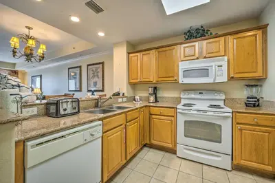 a kitchen with white appliances and wooden cabinets at 1 Mi to Disney Condo with Water-View Balcony! in Orlando