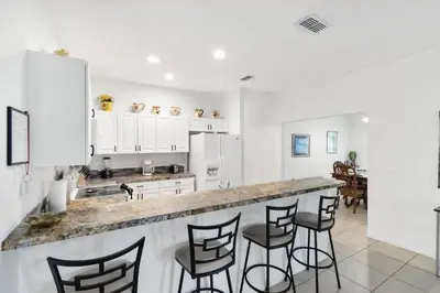 a kitchen with white cabinets and a counter with bar stools at Huge Screened Patio That Overlooks Lake Buck, Near Famous Attractions!! in Orlando