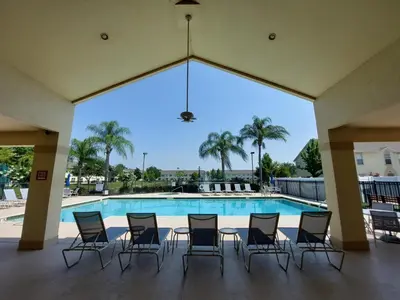 a group of chairs sitting around a pool at Amazing 32 Condo, Gated Community At Club Cortile!! in Kissimmee