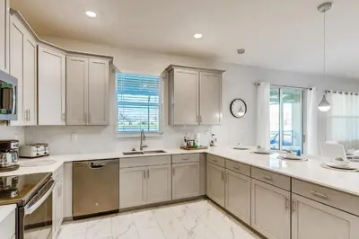 a kitchen with white cabinets and a clock on the wall at 2859 BD - Grand Luxury Villa with a Sparkling Pool in Kissimmee