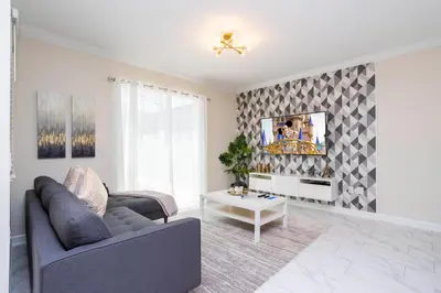 a living room with a couch and a tv on a wall at 2929 SS - Disney Delight: 4BR Pool Near Parks in Kissimmee