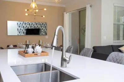 a kitchen with a sink and a living room at 2929 SS - Disney Delight: 4BR Pool Near Parks in Kissimmee