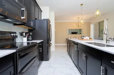 a kitchen with black cabinets and a black refrigerator at 2929 SS - Disney Delight: 4BR Pool Near Parks in Kissimmee