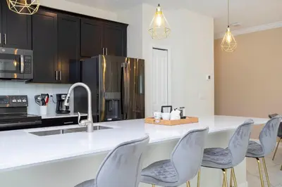 a kitchen with a counter with chairs and a sink at 2929 SS - Disney Delight: 4BR Pool Near Parks in Kissimmee