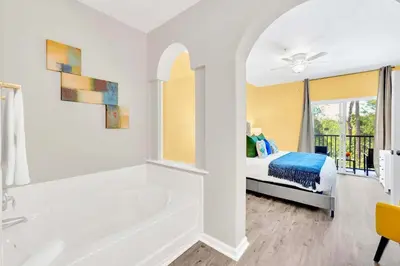 a white bathroom with a tub and a bed at 2BR Condo with Pool - Near Disney in Orlando
