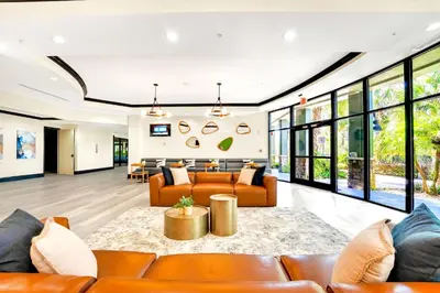 an open living room with leather furniture and large windows at 2BR Condo with Pool - Near Disney in Orlando
