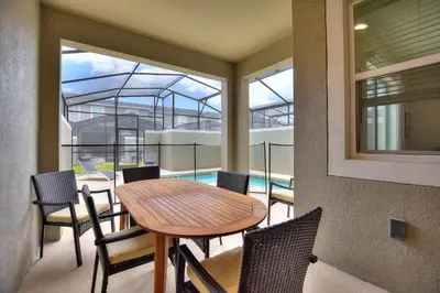 a balcony with a table and chairs and a pool at Barefoot Breeze - Storey Lake By Shine Villas #833 in Kissimmee