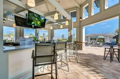 a patio with chairs and a bar with a flat screen tv at Magic Lily - Storey Lake By Shine Villas #834 in Kissimmee