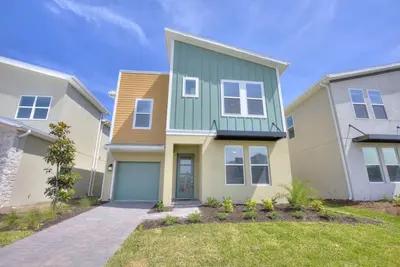 a large house with a green and white at Stars Align Storey Lake By Shine Villas #406 in Kissimmee