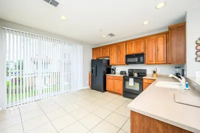 a kitchen with wooden cabinets and a black refrigerator at Beautiful Townhome, Vista Cay, Near Parks! 4018 in Orlando