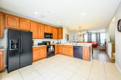 a kitchen with wooden cabinets and a black refrigerator at Beautiful Townhome, Vista Cay, Near Parks! 4018 in Orlando