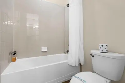 a white bathroom with a toilet and a bath tub at 350 Pendant · 350 Villa - 8BD - Private Pool - Game room in Orlando