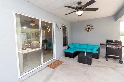 a screened in porch with a blue couch and a grill at Gorgeous Fully Furnished 2-Bedroom Luxury Villa in Kissimmee