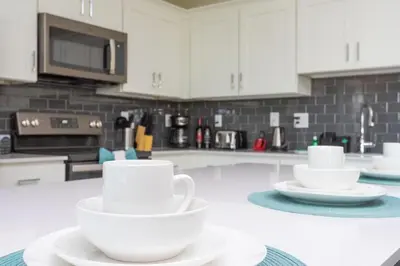 a kitchen with white cups and saucers on a counter at Sweet Suite Sleeps 6 Storey Lake By Shine Villas #903 in Kissimmee