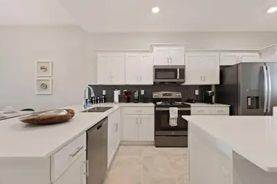 a kitchen with white cabinets and stainless steel appliances at Edgewater Escape At Storey Lake By Shine Villas #904 in Kissimmee