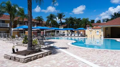 a resort pool with chairs and umbrellas at Enchanting Escape 3 Bedroom Minutes from Disney! in Kissimmee