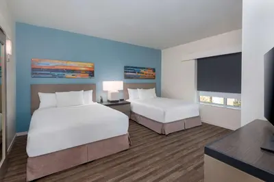 a hotel room with two beds and a flat screen tv at Hyatt House Orlando Airport in Orlando