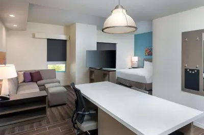 a hotel room with a bed and a living room at Hyatt House Orlando Airport in Orlando