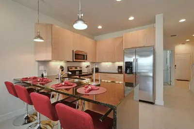 a kitchen with a table with red chairs and a refrigerator at 1523 Cozy Astonishing wPrivate Pool in Orlando
