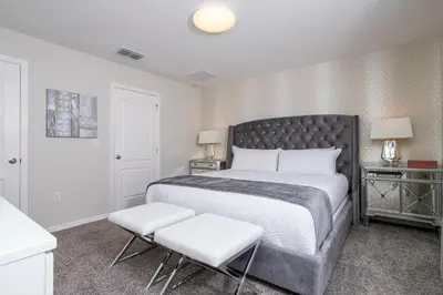 a bedroom with a large bed and two white chairs at 4774 Gorgeous Townhome in Kissimmee