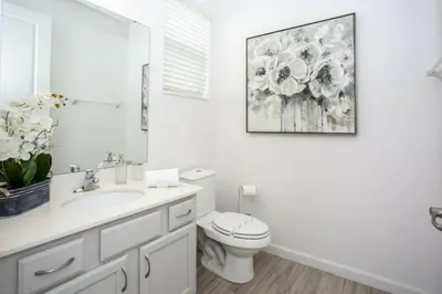 a white bathroom with a toilet and a picture on the wall at 2606YA Luxurious En-Suite Single Home Pool in Kissimmee