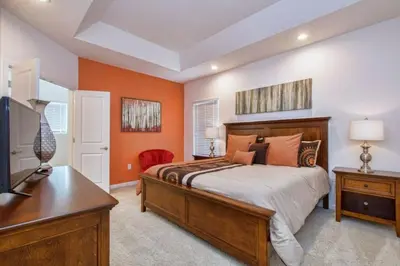 a bedroom with orange walls and a bed and a desk at 2600YA Luxury Gorgeous Private Pool in Kissimmee