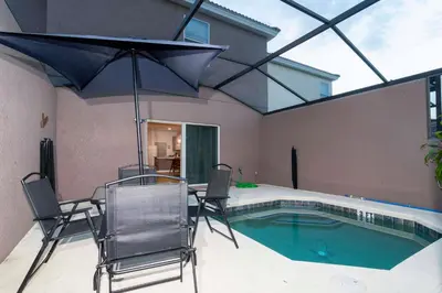 a patio with a table and chairs and a swimming pool at Cozy 3 bedroom home with Private Pool 4564 in Kissimmee