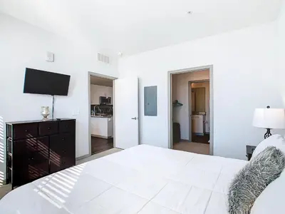 a white bedroom with a bed and a flat screen tv at Your Dream Apartment Stay in Kissimmee