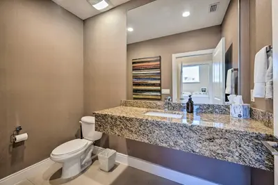 a bathroom with a toilet and a sink and a mirror at Upscale Townhome Close to Walt Disney World! in Orlando